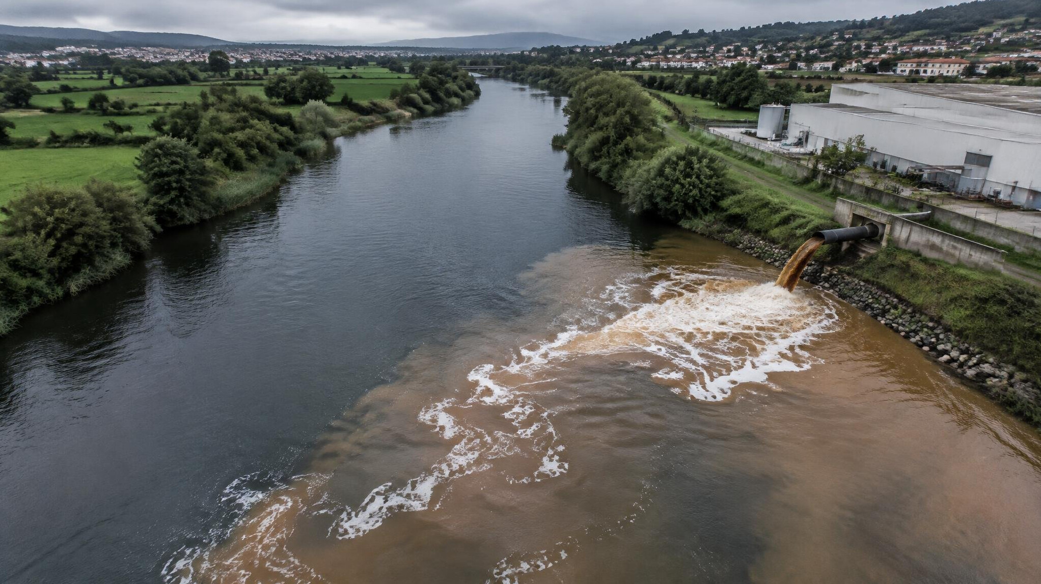 Aerial view of a discoloured river running past an industrial site in Portugal
